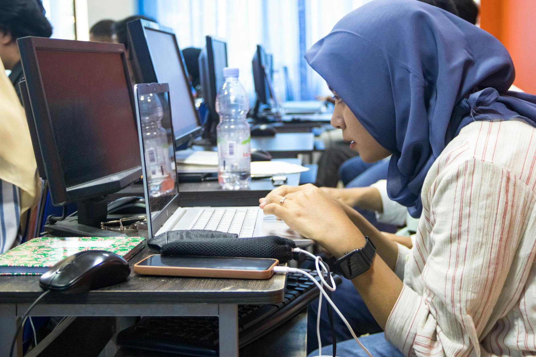 Młoda kobieta w hijabie pracuje na laptopie w sali komputerowej