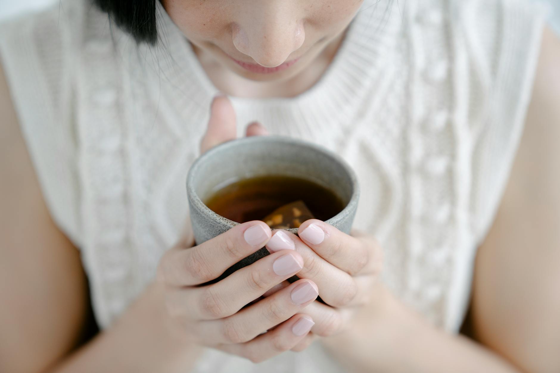 Kobieta wącha aromatyczną filiżankę gorącej herbaty na ból gardła